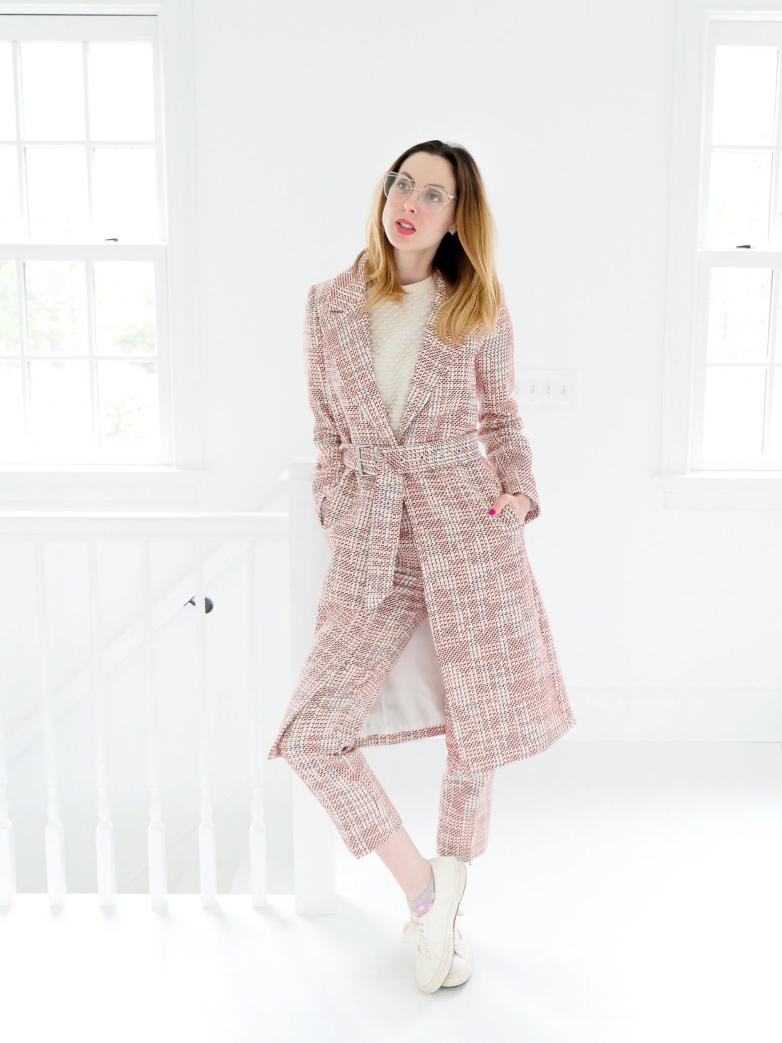 Eva Amurri Martino wears red and white patterned trousers, a matcing coat, and clear glasses in the studio of her Connecticut home