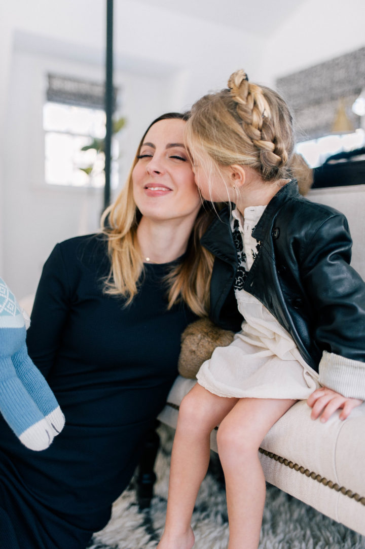 Eva Amurri Martino gets a kiss from her daughter Marlowe Mae, who is wearing an ivory tunic, leather jacket and a halo braid.