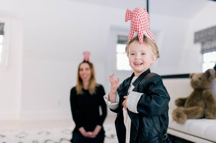 Marlow Mae Martino giggles with a toy elephant on her head, while mother Eva Amurri Martino watches on from behind her.