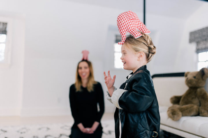 Marlow Mae Martino giggles with a toy elephant on her head, while mother Eva Amurri Martino watches on from behind her.