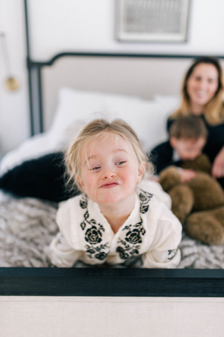 Marlowe Mae Martino makes funny faces at the foot of her parents bed, while mom Eva Amurri Martino watches on with brother Major.