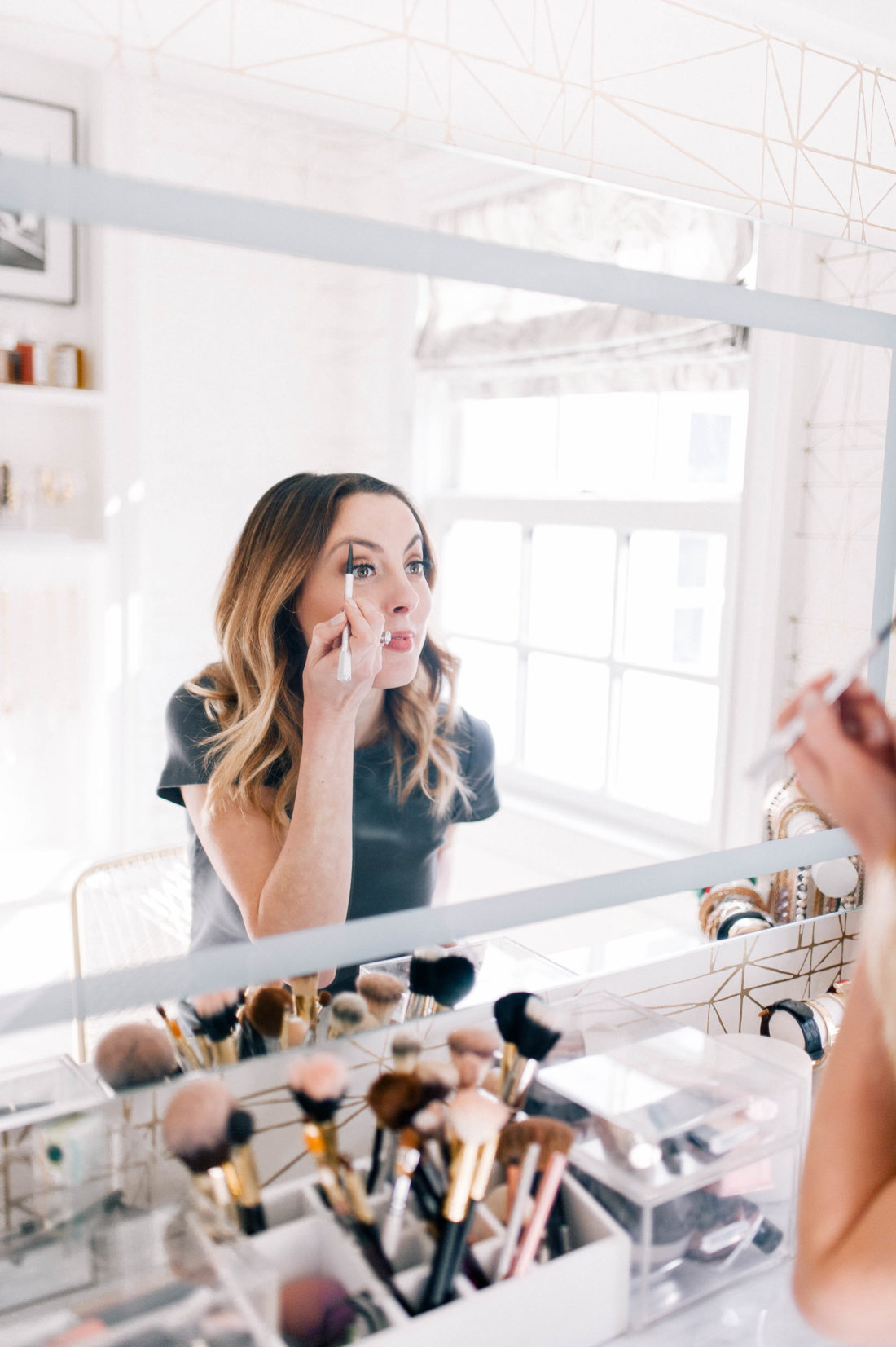 Eva Amurri Martino sits in the glam room of her Connecticut home, wearing floral pants and a grey tshirt, and fills in her eyebrows with an eyebrow pencil