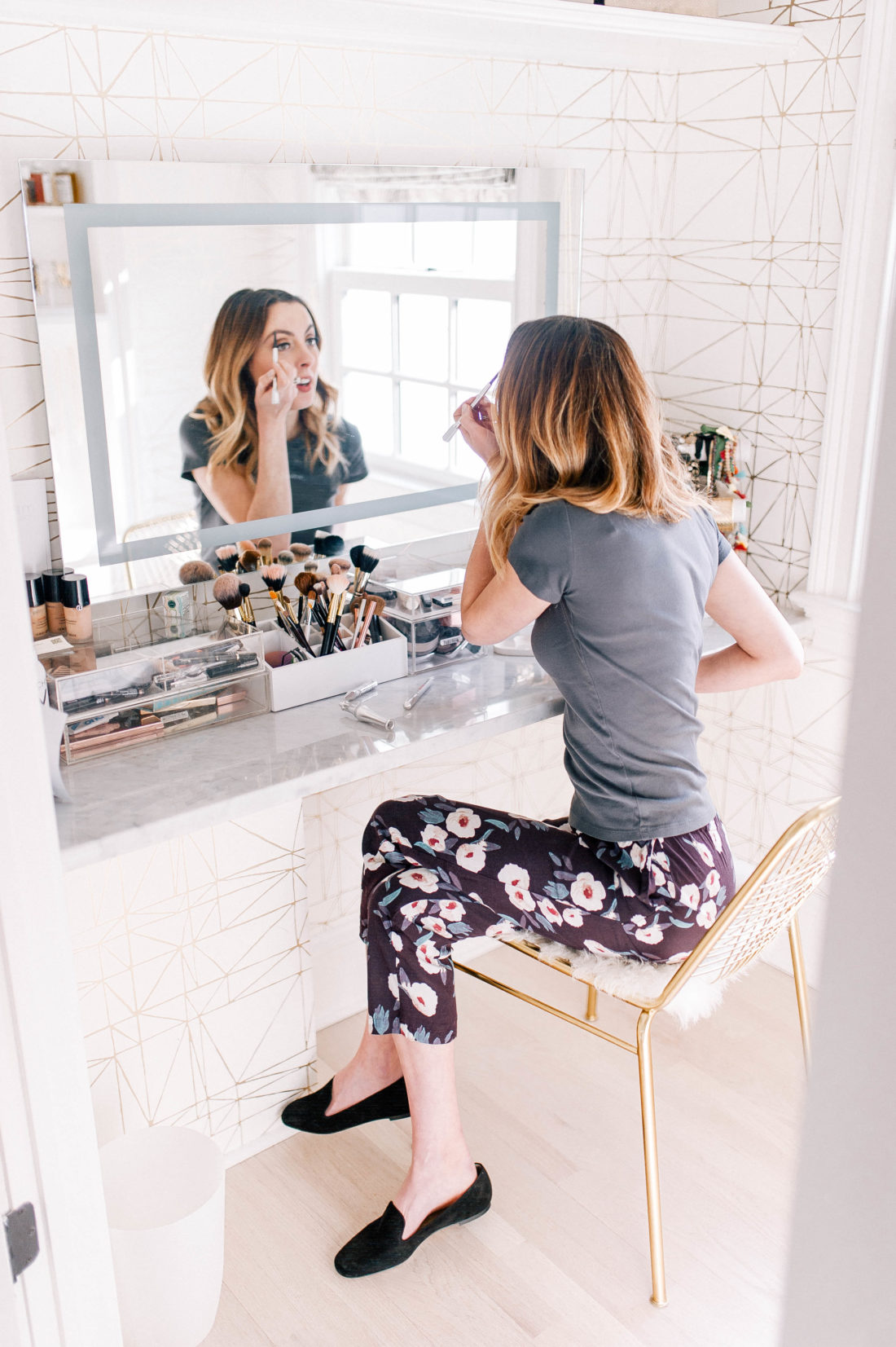 Eva Amurri Martino sits in the glam room of her Connecticut home, wearing floral pants and a grey tshirt, and fills in her eyebrows with an eyebrow pencil