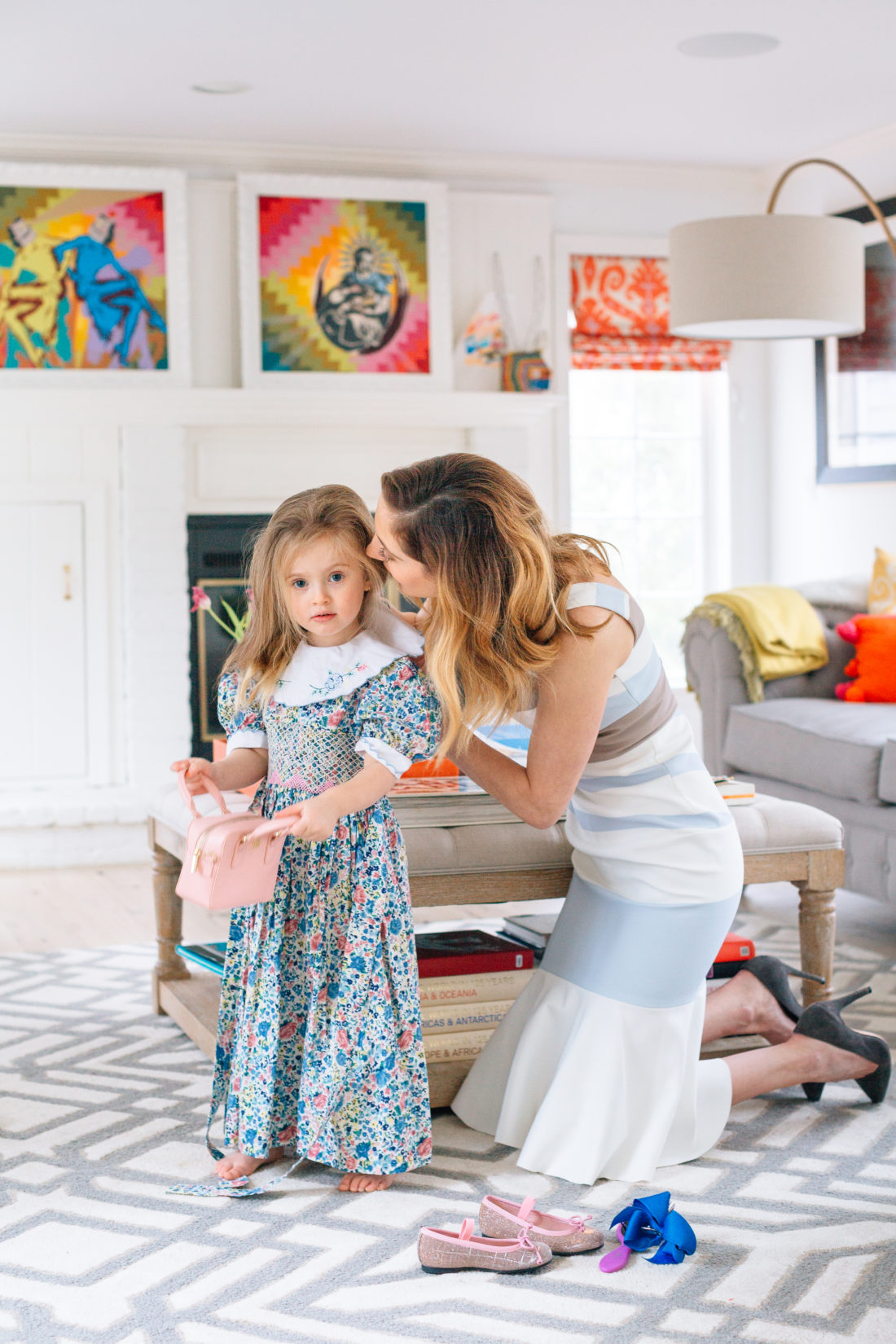 Eva Amurri Martino leans in to whisper in three year old daughter Marlowe's ear as she dresses her in a floral vintage smocked dress for easter and combs through her hair