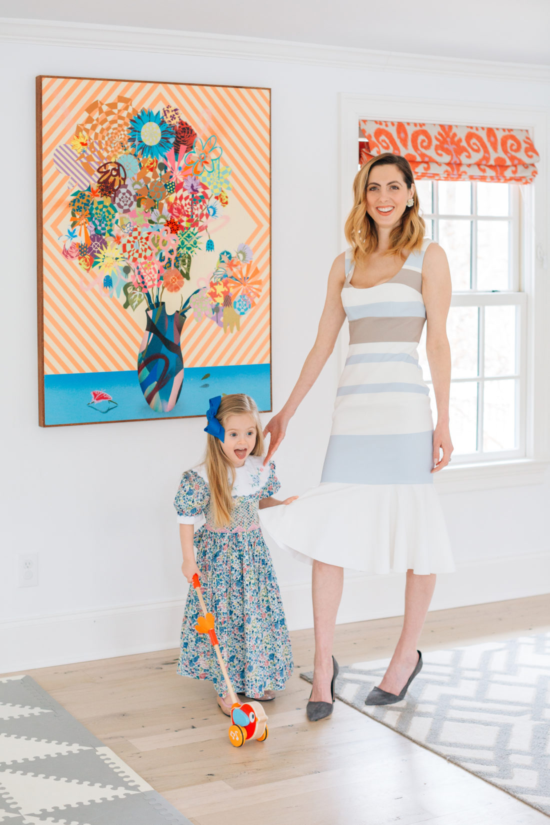 Eva Amurri Martino wears a striped Spring dress and stands with her three year old daughter who wears a floral dress with smocking for Easter