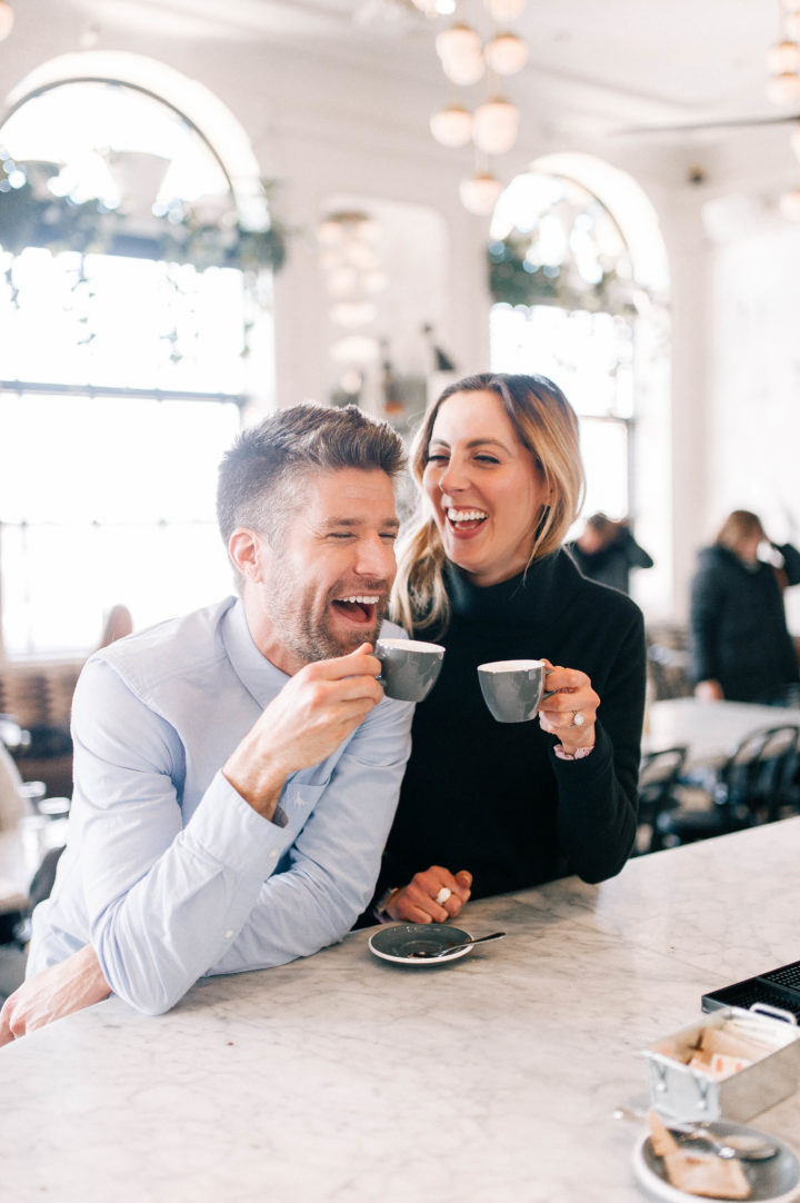 Eva Amurri Martino and Kyle Martino laugh together while drinking espresso at the bar of an NYC restaurant