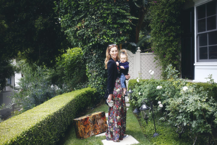 Eva Amurri Martino carrying her daughter Marlowe in a carrier with a suitcase ready to travel