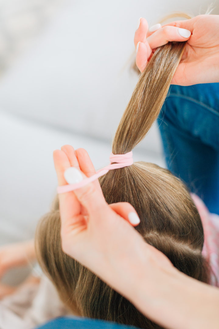 Eva Amurri Martino ties her daughter Marlowe's hair into a high poinytail with a pink hairtie.