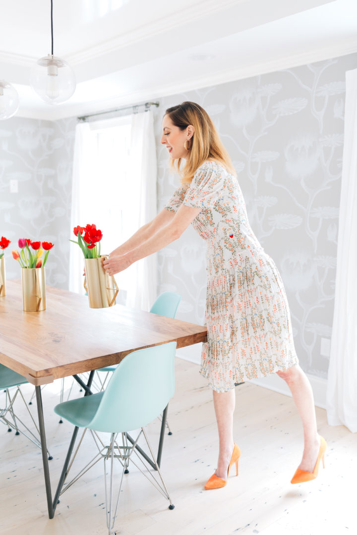 Eva Amurri Martino wears a vintage-inspired dress holding a gold vase full of red tulips