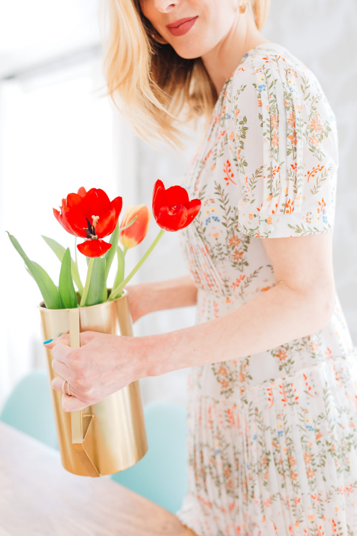 Eva Amurri Martino wears a vintage-inspired dress holding a gold vase full of red tulips