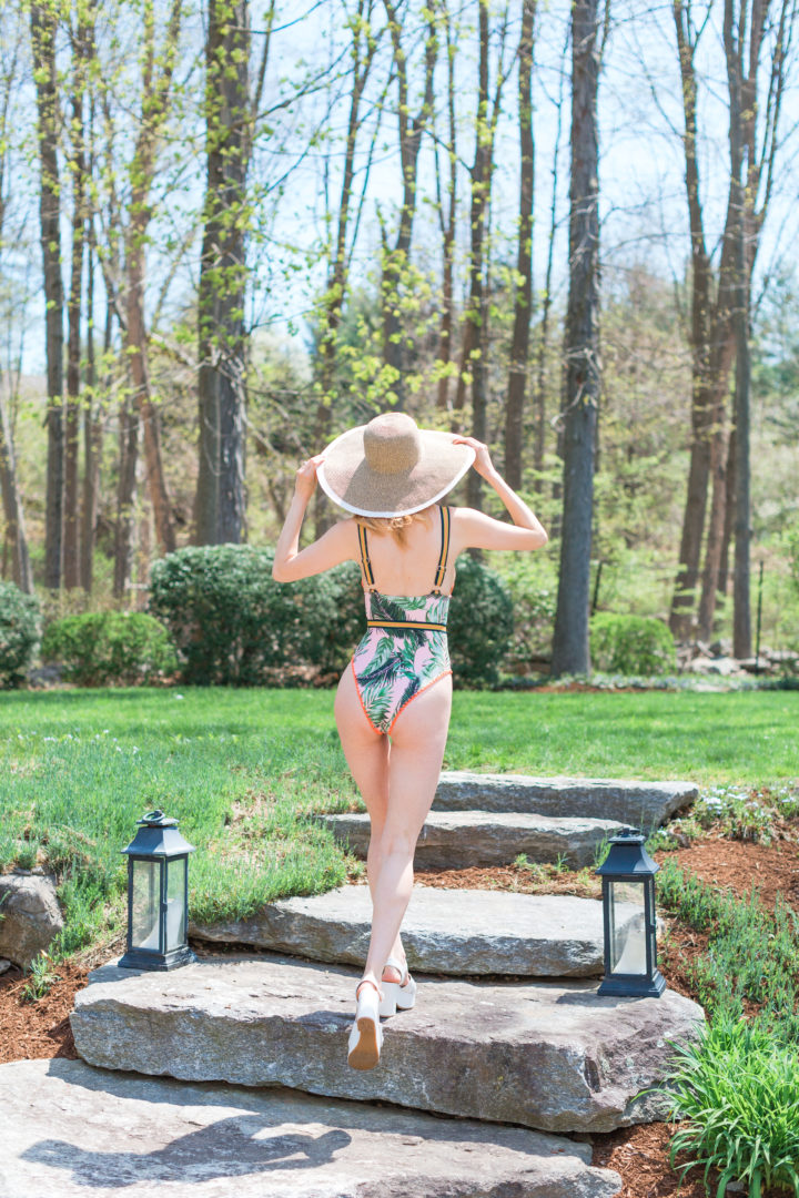 Eva Amurri Martino wears a jungle inspired one piece bathing suit and a large brim hat by her pool in Connecticut