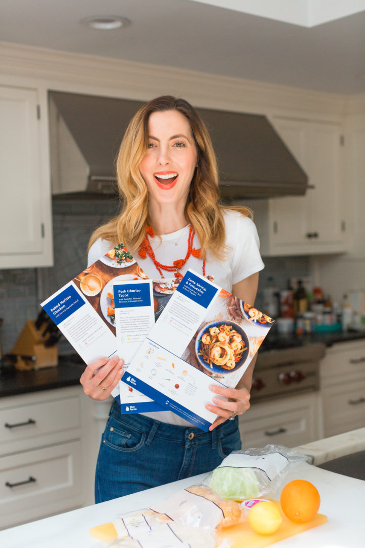 Eva Amurri Martino holds up Blue Apron meal plan recipes sheets.