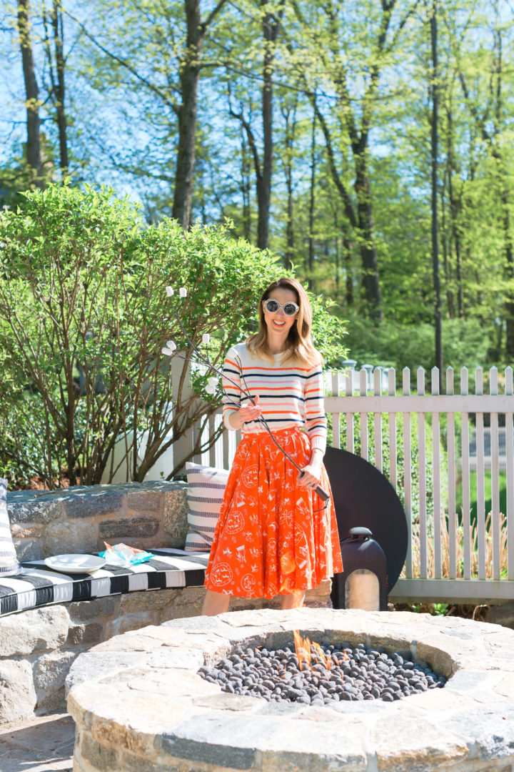 roasts marshmallows in a colorful frock at her Connecticut home