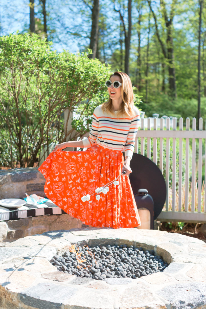 roasts marshmallows in a colorful frock at her Connecticut home