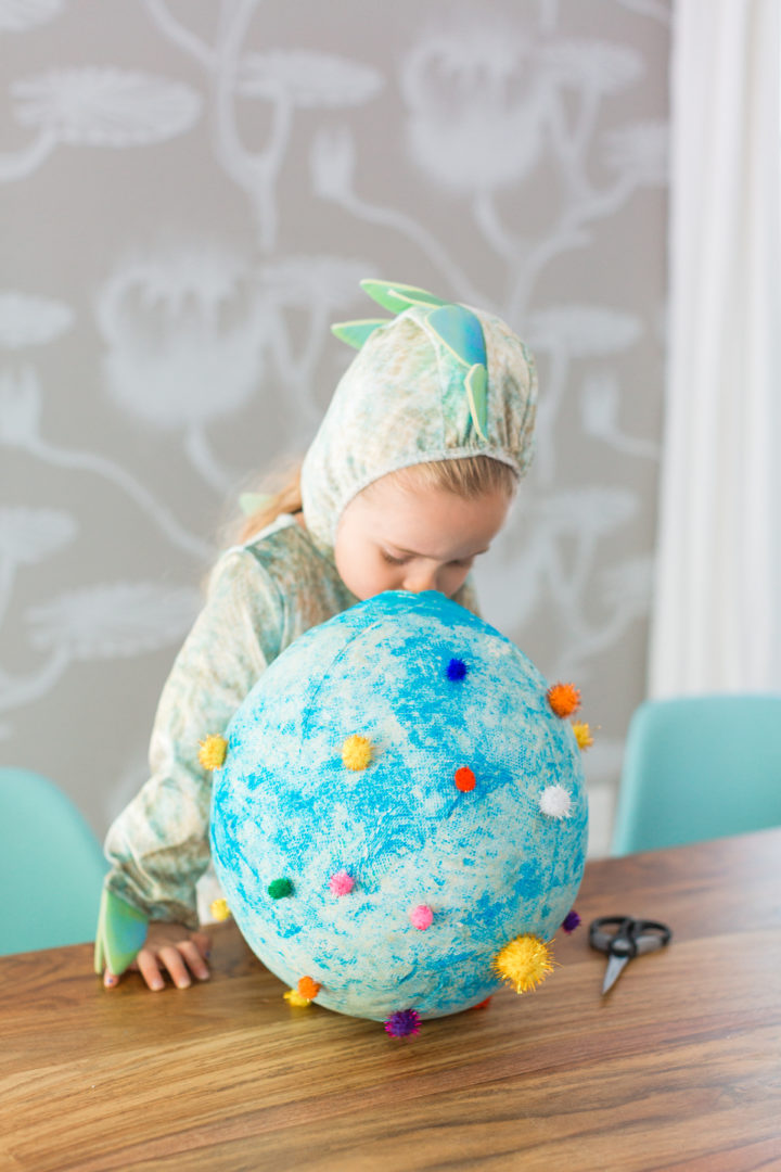 Eva Amurri Martino's daughter Marlowe wears a dinosaur costume and plays with a paper mache dinosaur egg