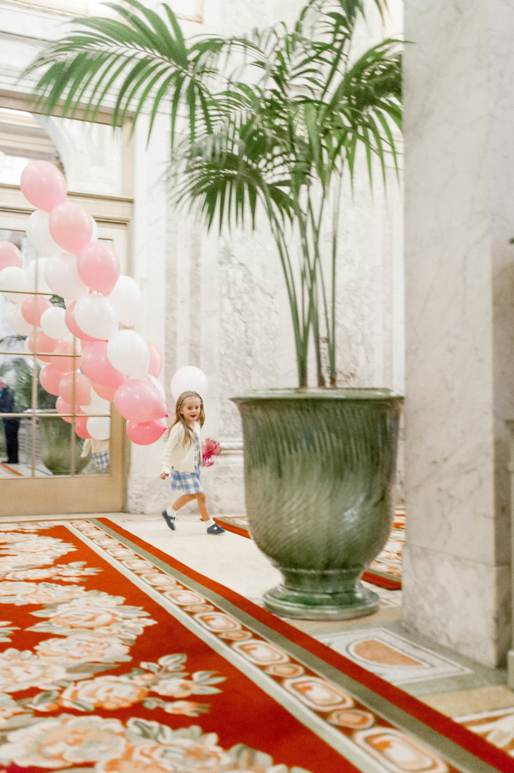 Eva Amurri Martino's daughter Marlowe carries pink and white balloons while walking through the iconic Plaza Hotel