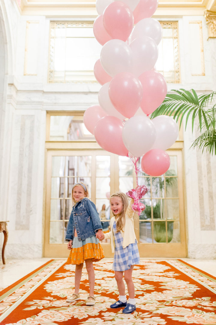 Eva Amurri Martino's daughter Marlowe carries pink and white balloons while walking through the iconic Plaza Hotel with a friend