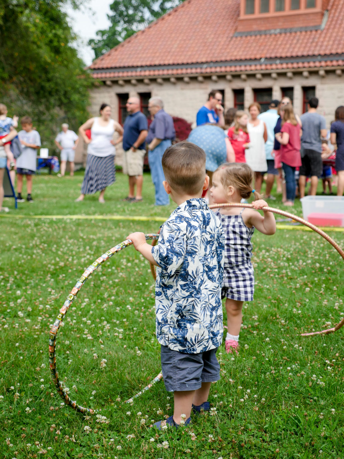 Major Martino wears a white and blue hawaiian shirt and plays with a hula hoop at a fourth of july lawn party