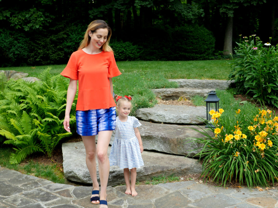 Eva and Marlowe Martino walk through their backyard wearing red white and blue on the fourth of july