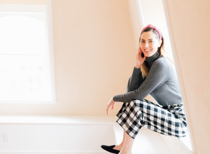 Eva Amurri Martino wears checked trousers and a grey cashmere sweater, and sits in her empty home that awaits renovations