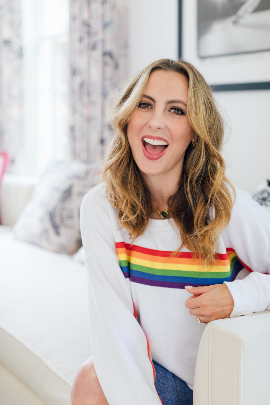 Eva Amurri Martino smiles in a rainbow sweatshirt showing off her easy pretty curls