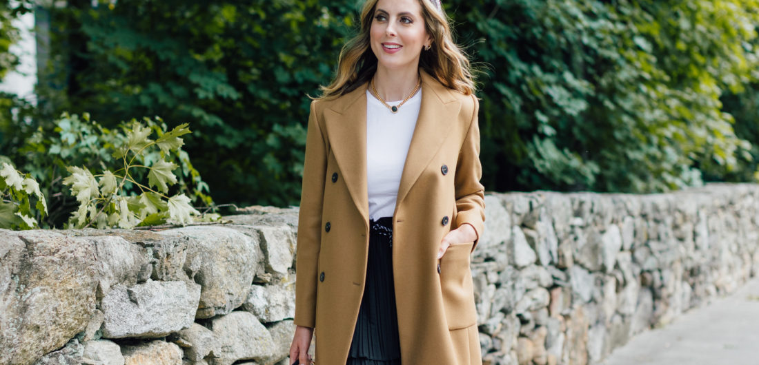 Eva Amurri Martino wears a camel coat, a black skirt and a white top as a neutral color palatte