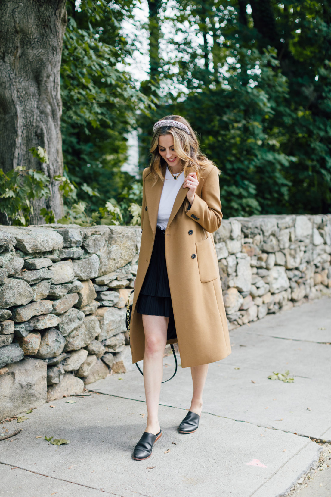 Eva Amurri Martino wears a camel coat, a black skirt and a white top as a neutral color palette