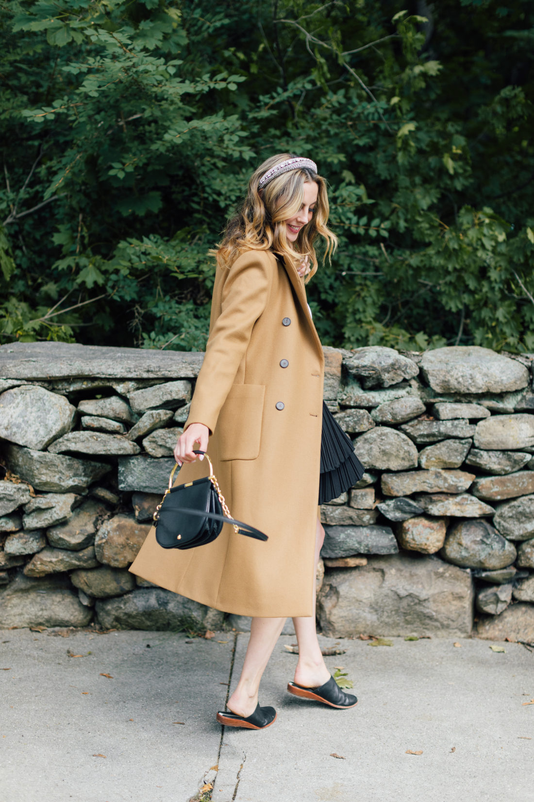 Eva Amurri Martino wears a camel coat, a black skirt and a white top as a neutral color palette