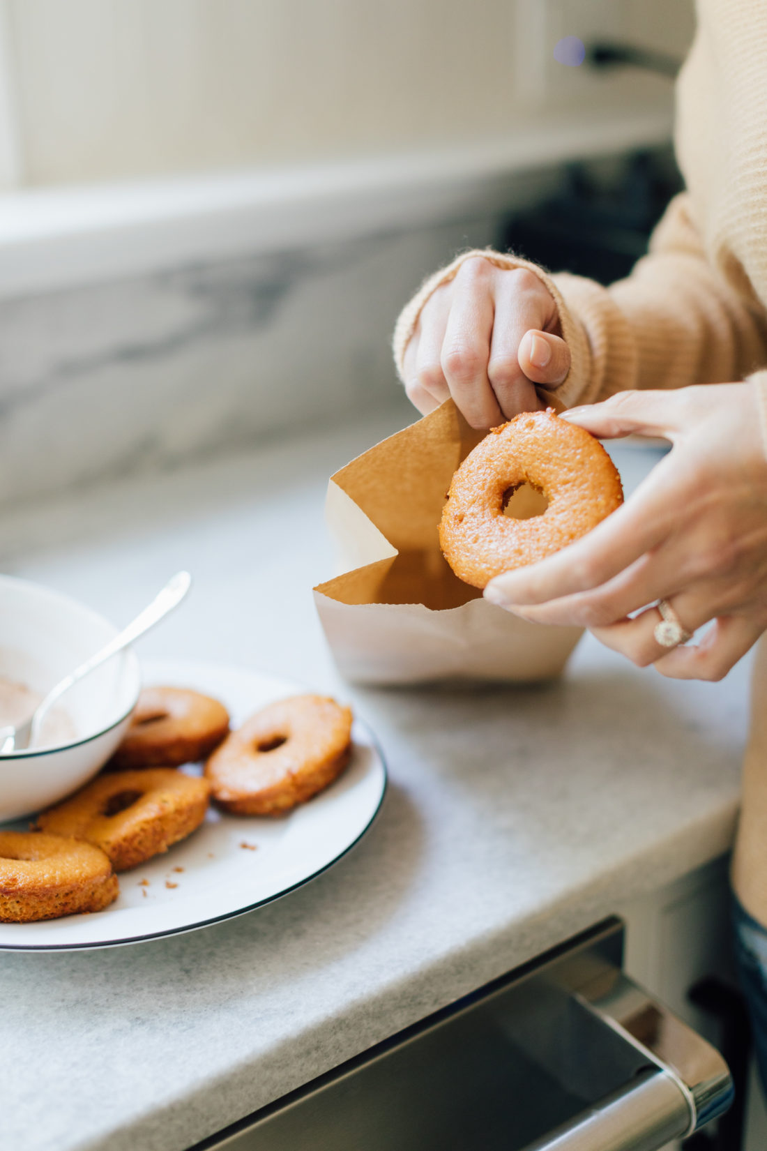 Eva Amurri Martino places a baked apple cider donut inside a brown paper bag