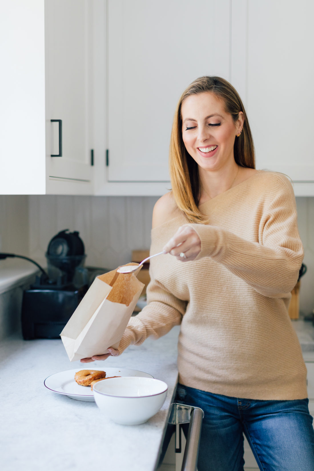 Eva Amurri Martino shakes up her baked apple cider donuts in a brown bag with sugar