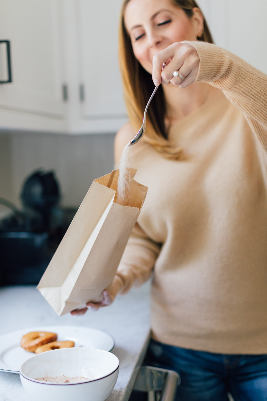 Eva Amurri Martino shakes up her baked apple cider donuts in a brown bag with sugar