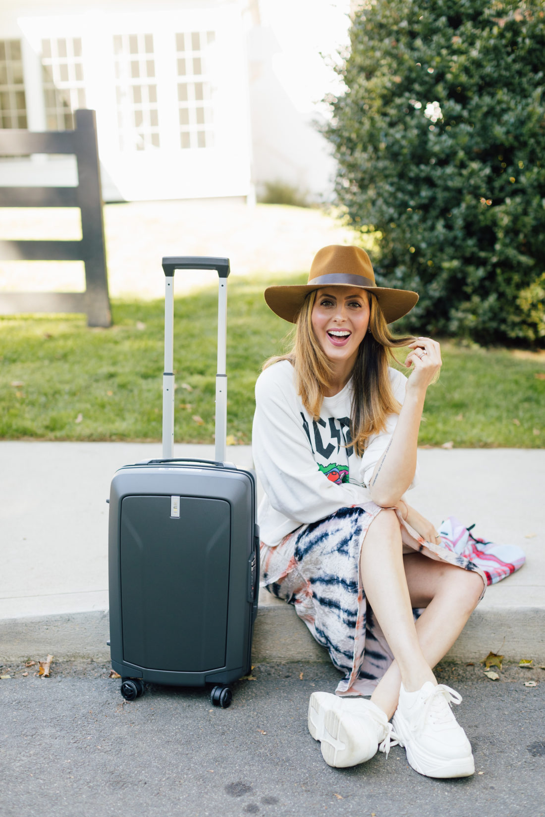 Eva Amurri Martino wears festival chic clothing and poses with Thule luggage outside her connecticut home