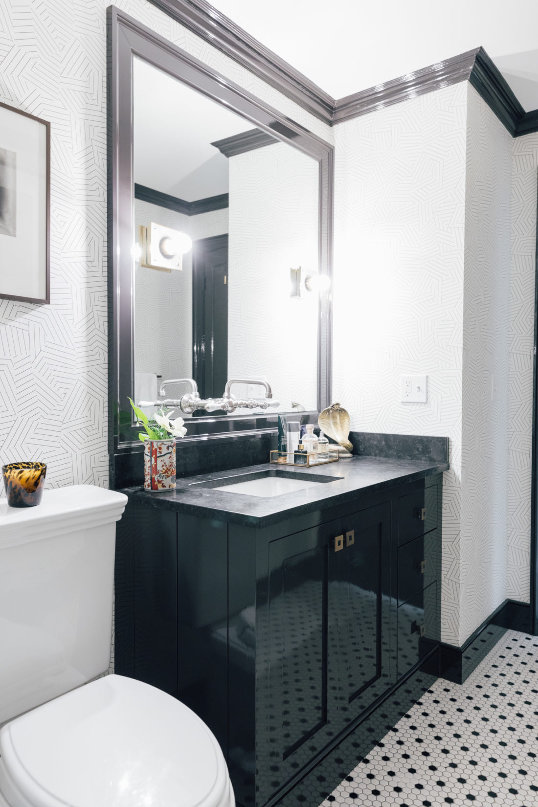 A custom mirror with Urban Electric Pop Sconces that hangs over the Saint Henry Black granite countertop from Polycor inside Kyle Martino's masculine bathroom in his newly renovated Connecticut home