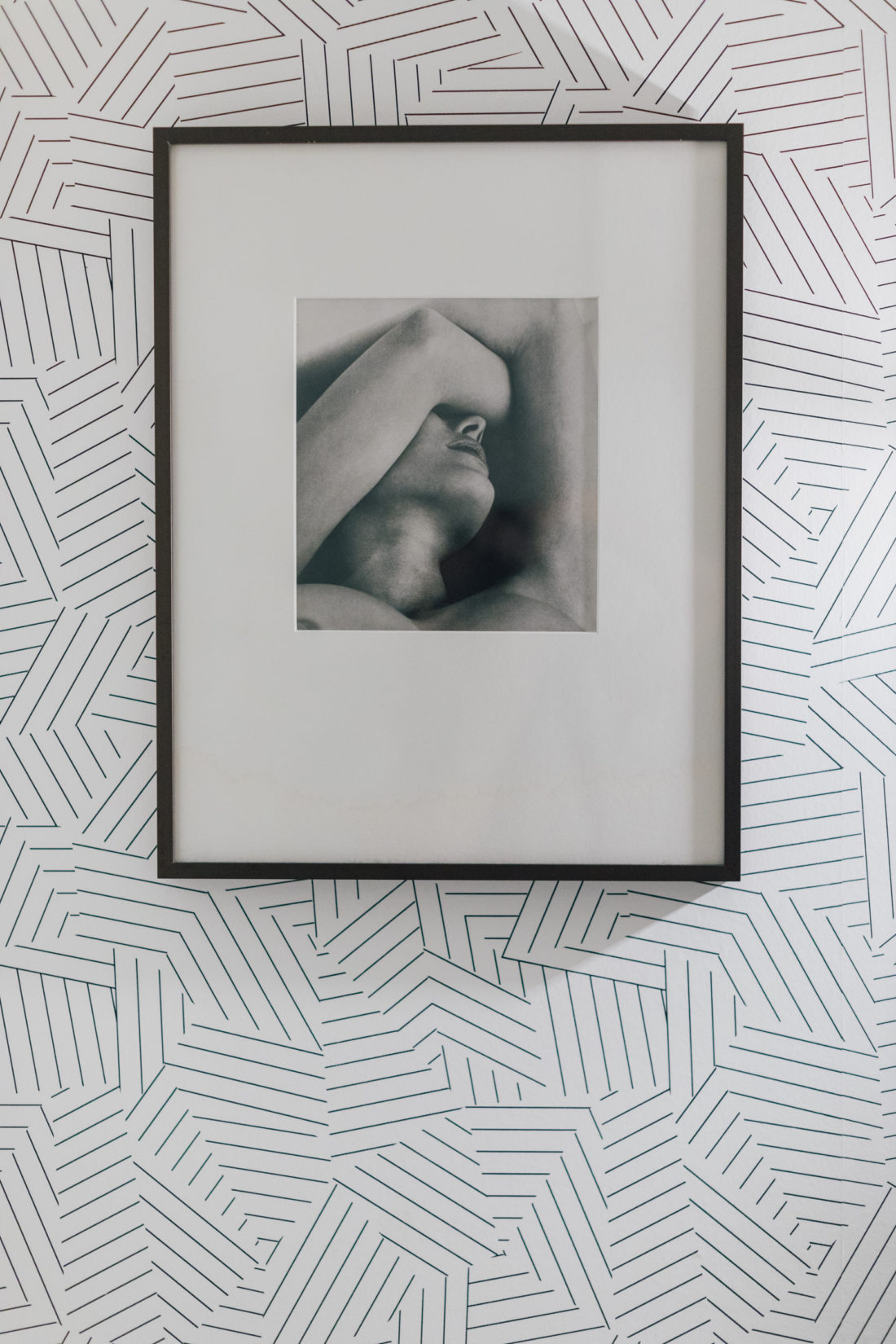 Schumacher's Deconstructed Stripe Wallpaper in Black sets a light backdrop to the black and white photographs that hang in Kyle Martino's newly renovated his & hers bathroom.