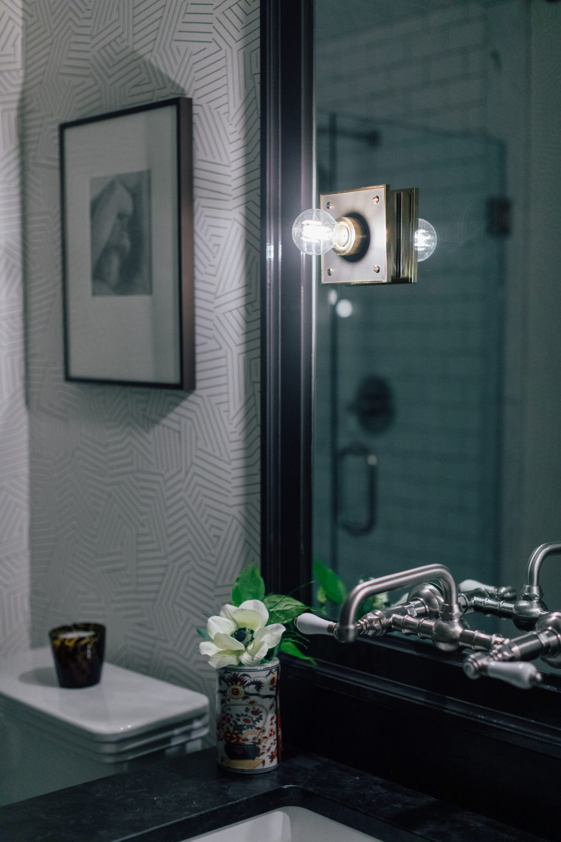 A custom mirror with Urban Electric Pop Sconces that hangs over the Saint Henry Black granite countertop from Polycor inside Kyle Martino's masculine bathroom in his newly renovated Connecticut home