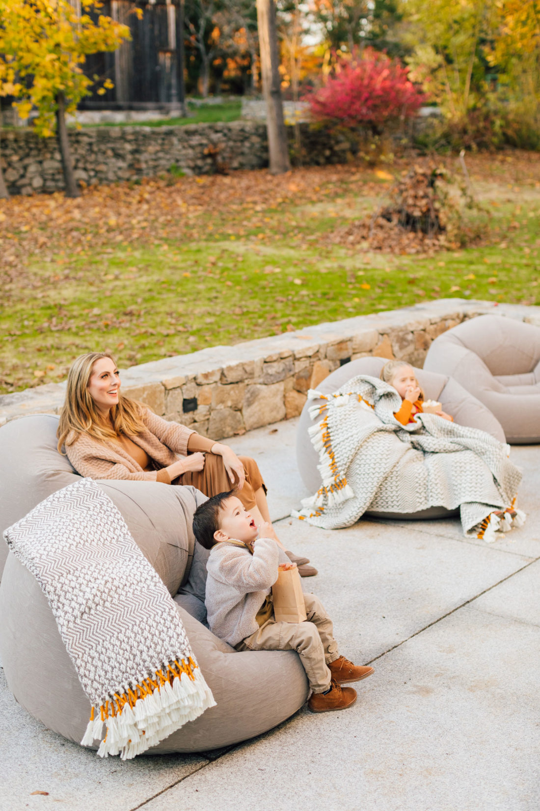 Eva Amurri and kids Marlowe and Major sit on beanbag chairs for an outdoor movie night on the back patio of her Connecticut home